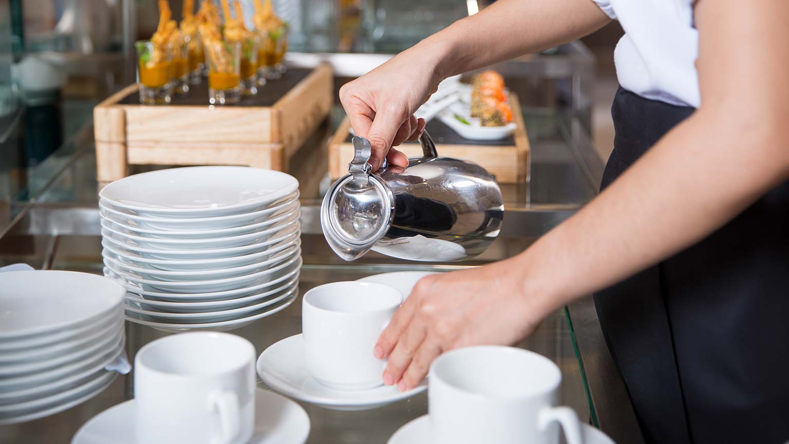 Un cameriere versa caffè in una tazza durante un coffee break aziendale, creando un momento di servizio elegante e accogliente.